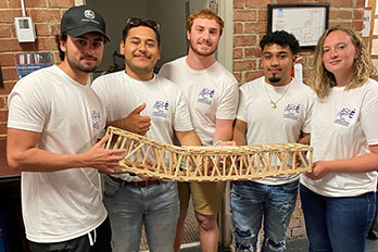  students holding a wooden bridge