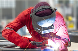  a welder works while covered with protective gear